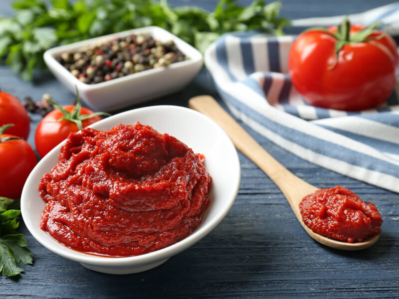 adding tomato paste to sauce